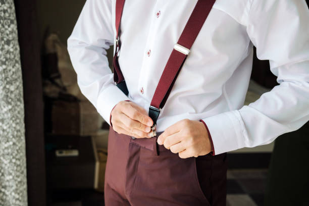 Unrecognizable man showing off his business or festive bow. Holding on to suspenders in white shirt wearing bow tie