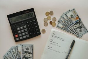 A calculator, notes and dollar bills on the table. Budgeting as one of many office relocation challenges in Miami