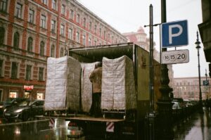 A moving truck with belongings in it and a man on a rainy day